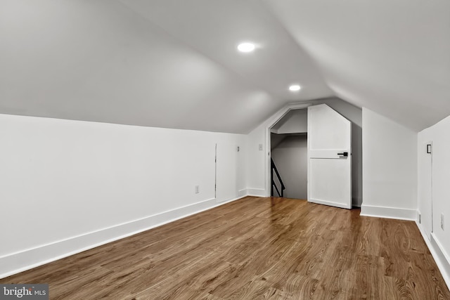 additional living space featuring vaulted ceiling, wood finished floors, baseboards, and recessed lighting
