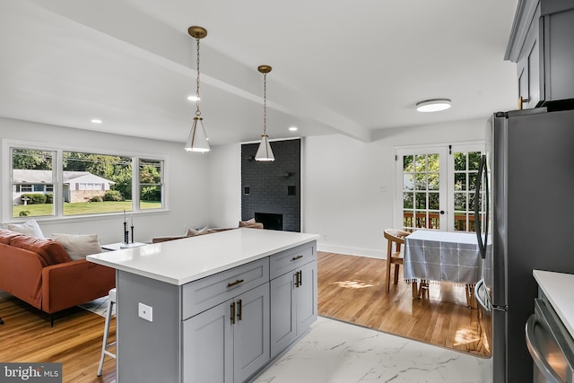 kitchen featuring appliances with stainless steel finishes, gray cabinets, open floor plan, a fireplace, and healthy amount of natural light