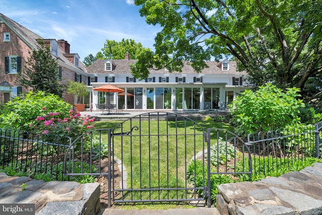 back of property with a lawn, a chimney, fence, a patio, and a gate