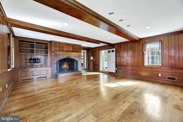 unfurnished living room featuring a brick fireplace, hardwood / wood-style floors, beam ceiling, and visible vents