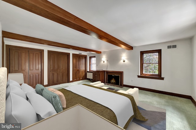 carpeted bedroom featuring baseboards, a warm lit fireplace, multiple windows, and visible vents