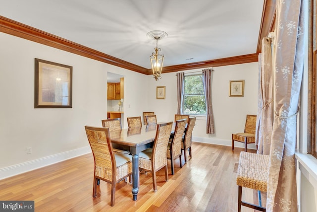 dining room featuring light wood finished floors, an inviting chandelier, baseboards, and ornamental molding
