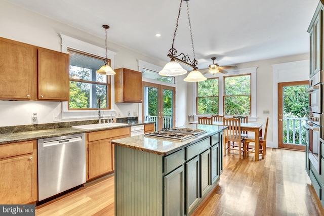 kitchen featuring french doors, a sink, light wood-type flooring, ceiling fan, and appliances with stainless steel finishes