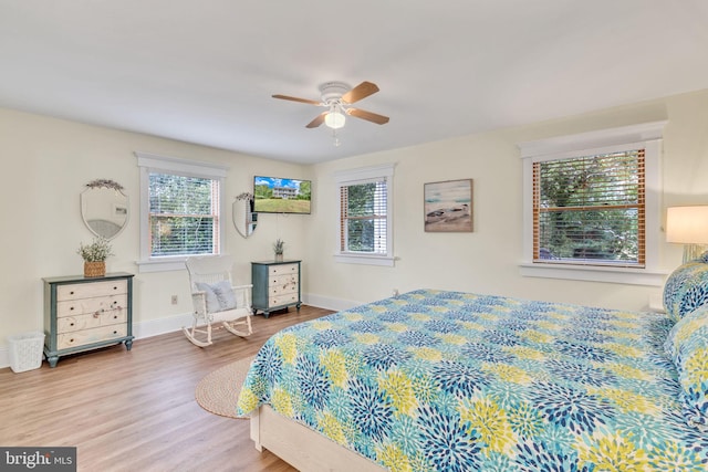 bedroom featuring baseboards, multiple windows, a ceiling fan, and wood finished floors