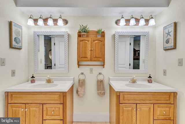 bathroom featuring baseboards, two vanities, and a sink