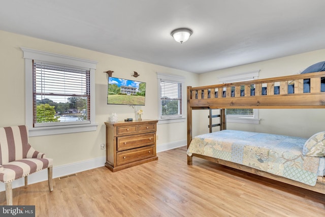 bedroom with visible vents, wood finished floors, and baseboards