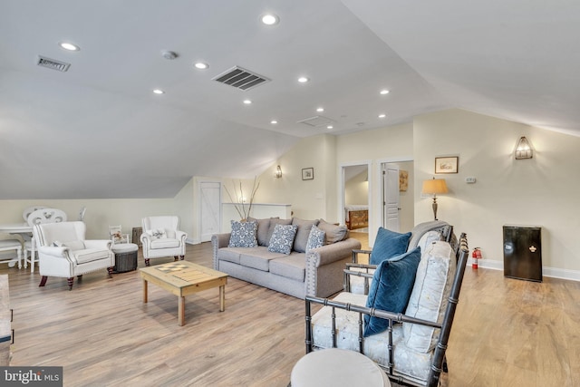 living area featuring light wood finished floors, lofted ceiling, and visible vents