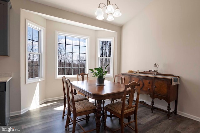 dining space featuring dark wood-style flooring, baseboards, and a notable chandelier