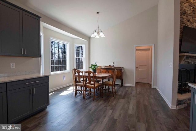 dining space with dark wood finished floors, a chandelier, baseboards, and high vaulted ceiling