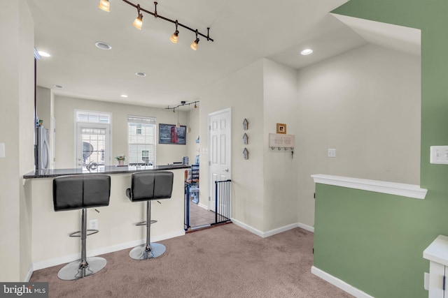 kitchen with freestanding refrigerator, a breakfast bar area, recessed lighting, baseboards, and carpet flooring