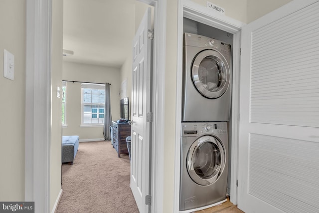 washroom with stacked washer and clothes dryer, laundry area, baseboards, and carpet floors