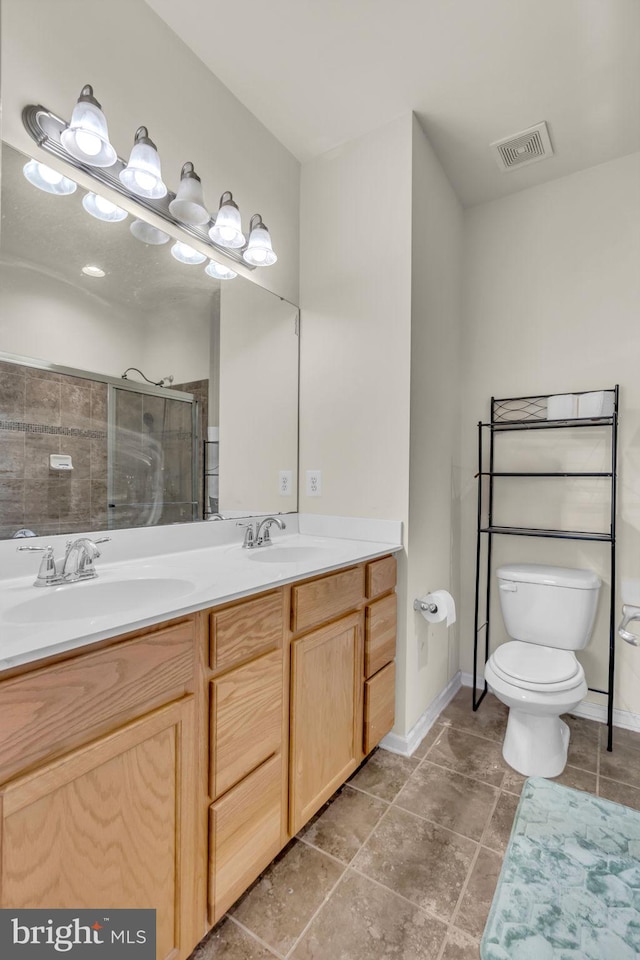 bathroom with toilet, visible vents, a shower stall, and a sink