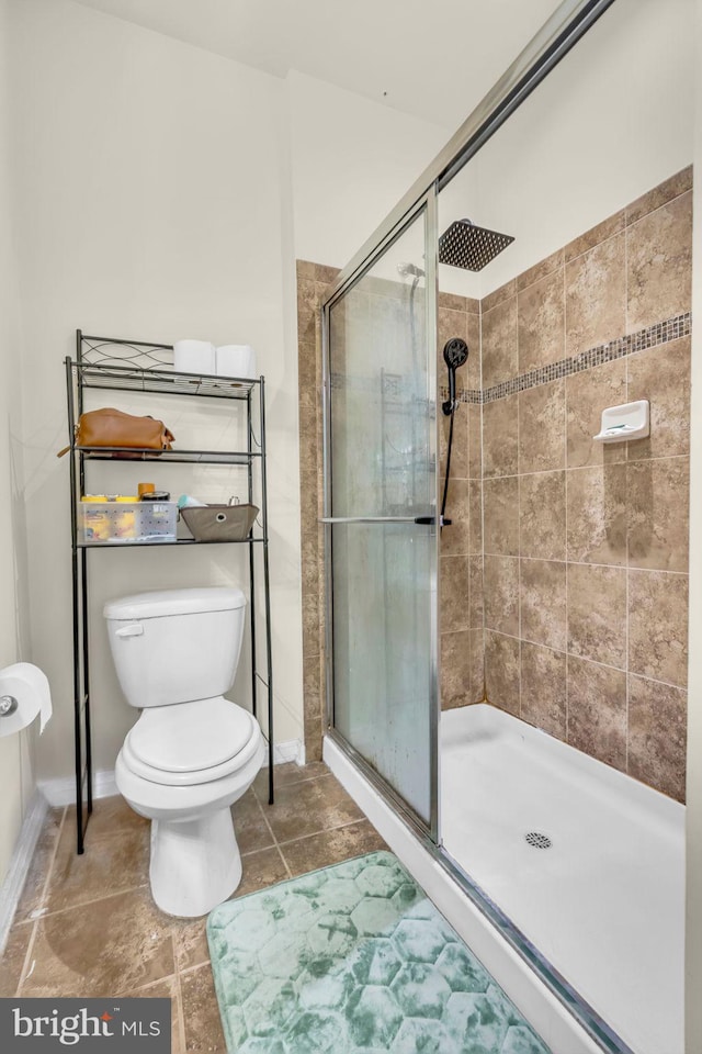full bathroom featuring a stall shower, toilet, baseboards, and tile patterned floors