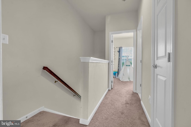 hall with baseboards, an upstairs landing, and carpet floors