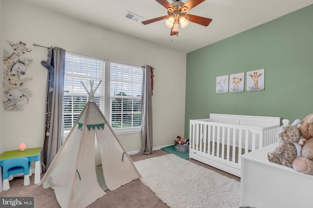 bedroom with carpet floors, a nursery area, baseboards, and visible vents