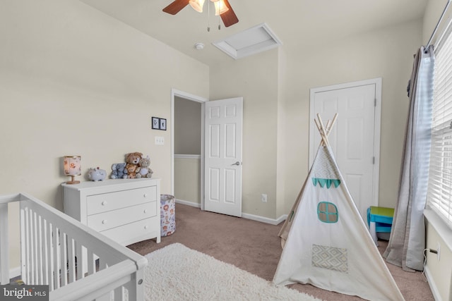 bedroom with attic access, baseboards, carpet flooring, a nursery area, and ceiling fan