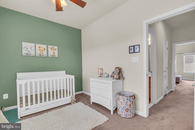 carpeted bedroom featuring ceiling fan, baseboards, and a nursery area