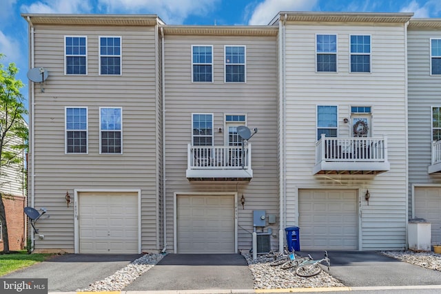 view of property featuring central air condition unit, driveway, and an attached garage