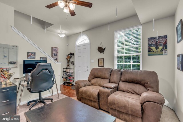 living area featuring baseboards, light carpet, and ceiling fan