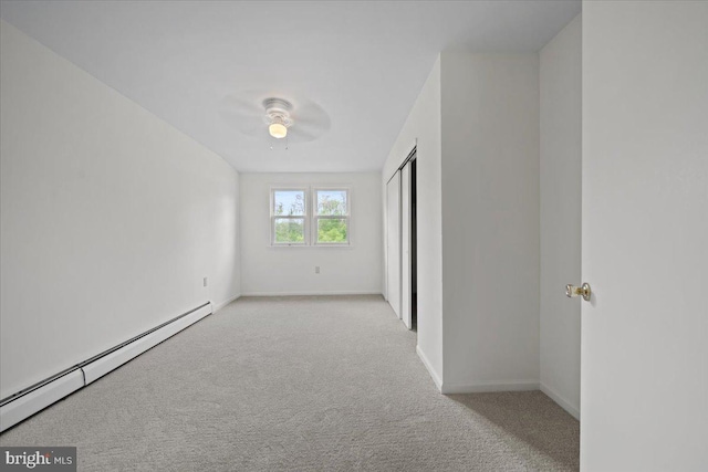 carpeted spare room with baseboards, a ceiling fan, and a baseboard heating unit