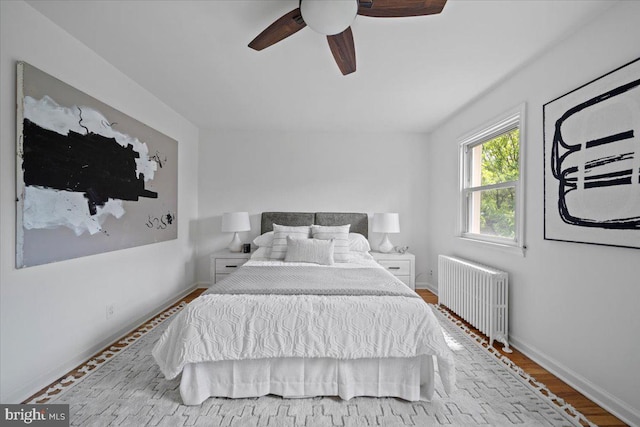 bedroom with wood finished floors, baseboards, ceiling fan, and radiator heating unit