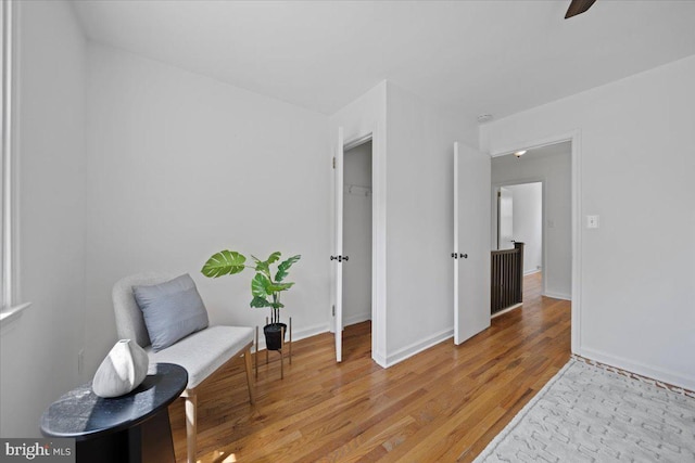 sitting room with light wood-style floors, baseboards, and a ceiling fan