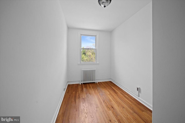 unfurnished room with radiator, wood finished floors, and baseboards