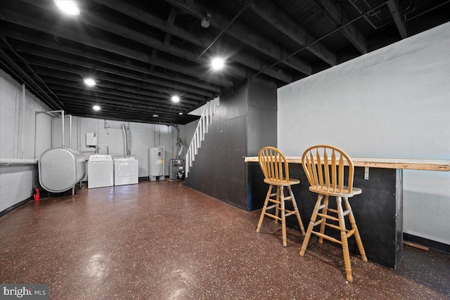 finished basement featuring washing machine and dryer, water heater, heating fuel, a dry bar, and stairs