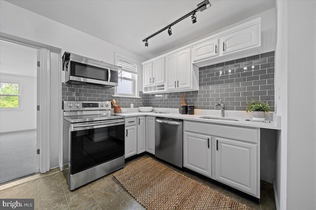 kitchen featuring white cabinets, appliances with stainless steel finishes, a healthy amount of sunlight, and a sink