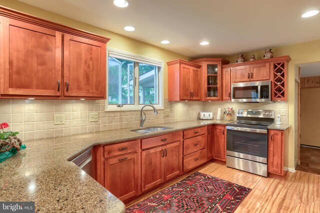 kitchen with stainless steel appliances, a sink, light stone countertops, recessed lighting, and decorative backsplash