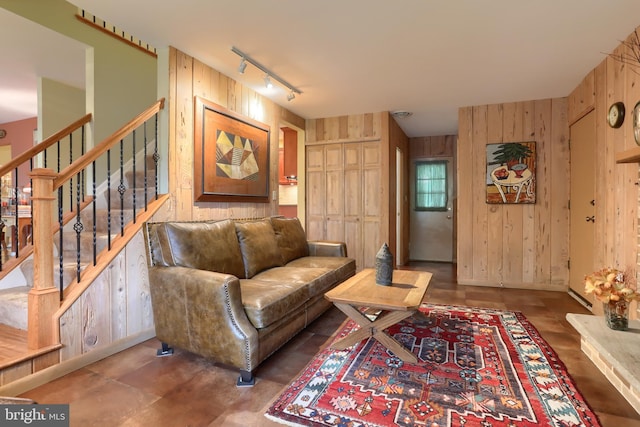 living area featuring wood walls, rail lighting, and stairway