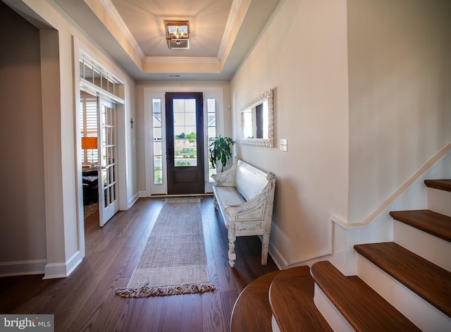 foyer with a tray ceiling, baseboards, crown molding, stairway, and dark wood-style floors
