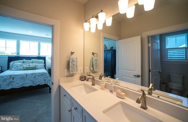 ensuite bathroom with double vanity, ensuite bath, toilet, and a sink