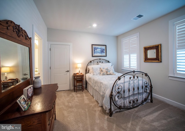 bedroom featuring light carpet, baseboards, visible vents, and multiple windows