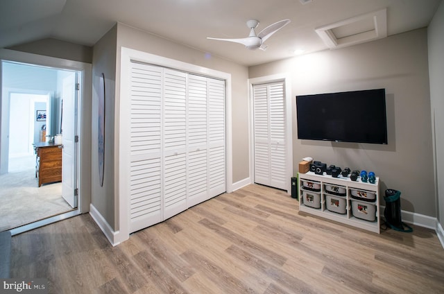 interior space with baseboards, attic access, a ceiling fan, and wood finished floors