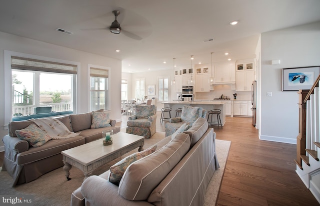 living room with a ceiling fan, stairs, light wood-style flooring, recessed lighting, and baseboards