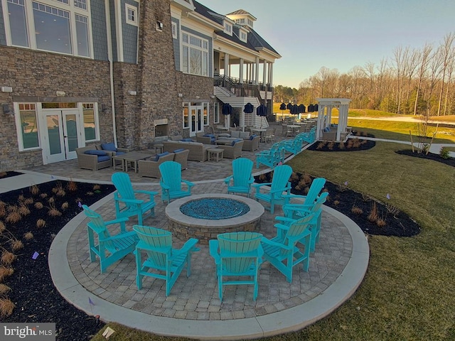 view of patio / terrace featuring a balcony, an outdoor living space with a fire pit, and french doors