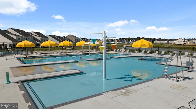 pool featuring a residential view, a water slide, fence, and a water play area