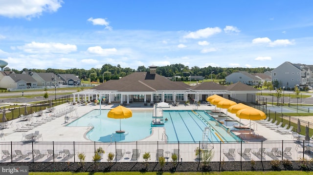 pool featuring a patio area, a residential view, a water slide, and fence