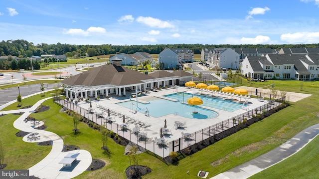 community pool featuring a yard, a residential view, and fence