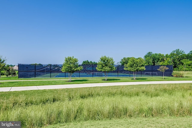 exterior space with a tennis court and fence
