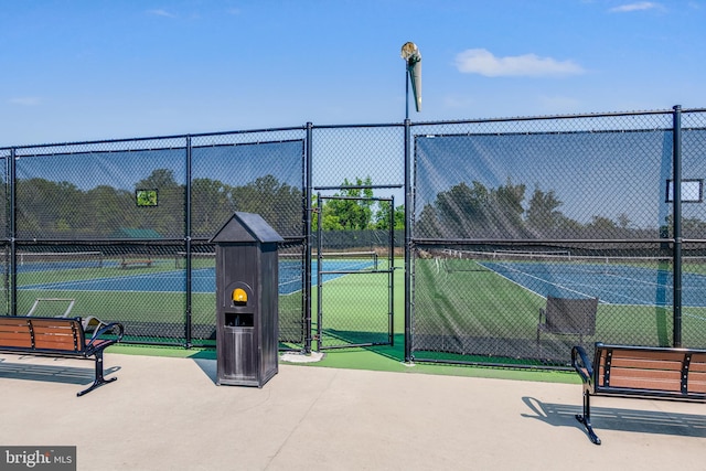 view of tennis court featuring fence and a gate