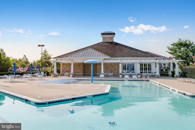 community pool with a patio, a pergola, and fence