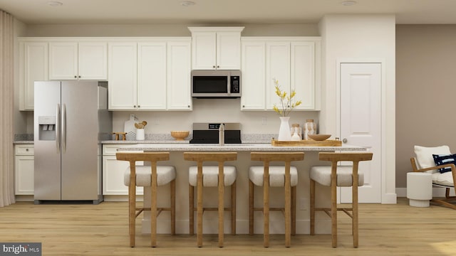 kitchen with white cabinets, a kitchen breakfast bar, light wood-type flooring, and appliances with stainless steel finishes