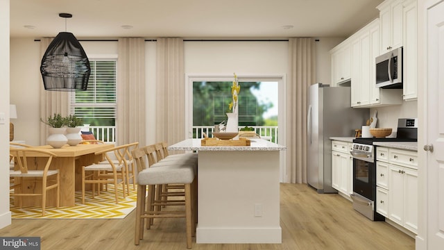 kitchen with stainless steel appliances, a kitchen breakfast bar, light wood-type flooring, white cabinets, and a kitchen island