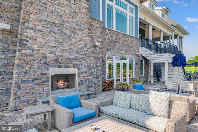 view of patio featuring an outdoor living space with a fireplace, french doors, and a balcony