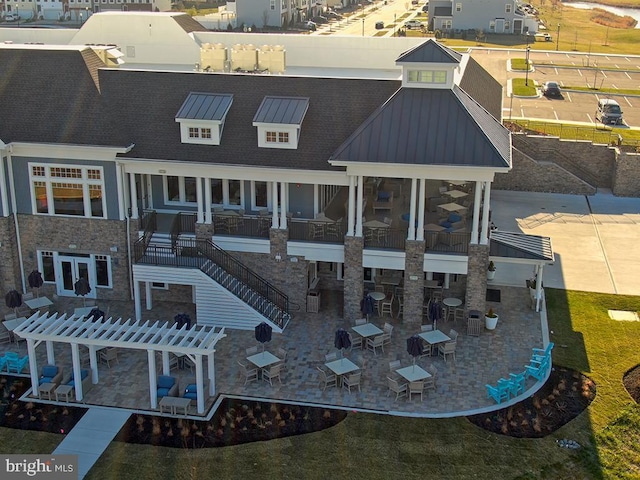 rear view of property with a standing seam roof, metal roof, a patio, stairs, and a pergola