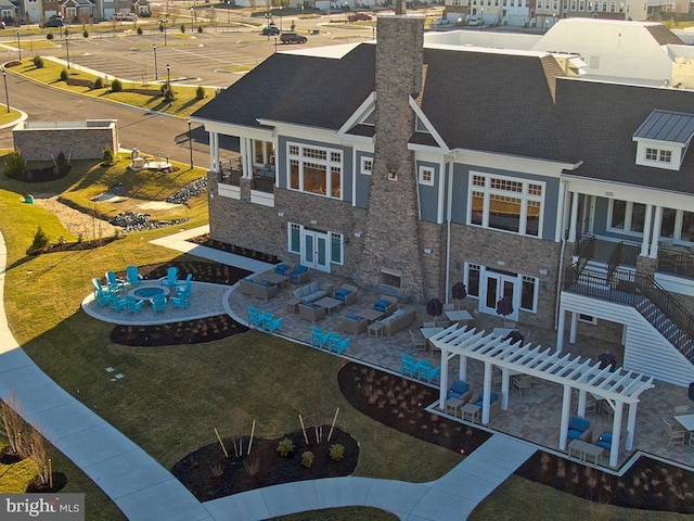 rear view of property featuring stone siding, a residential view, a patio, a pergola, and a chimney