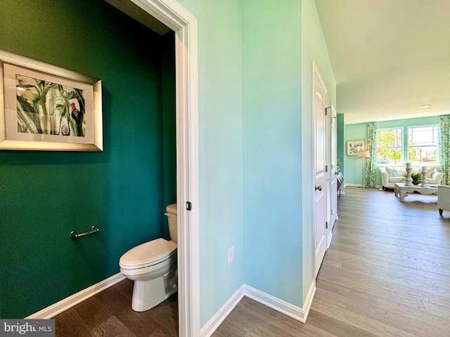bathroom with toilet, baseboards, and wood finished floors