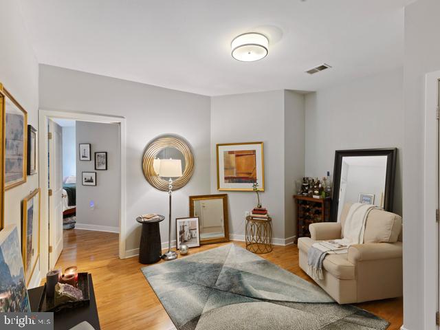 sitting room with light wood-style floors, visible vents, and baseboards